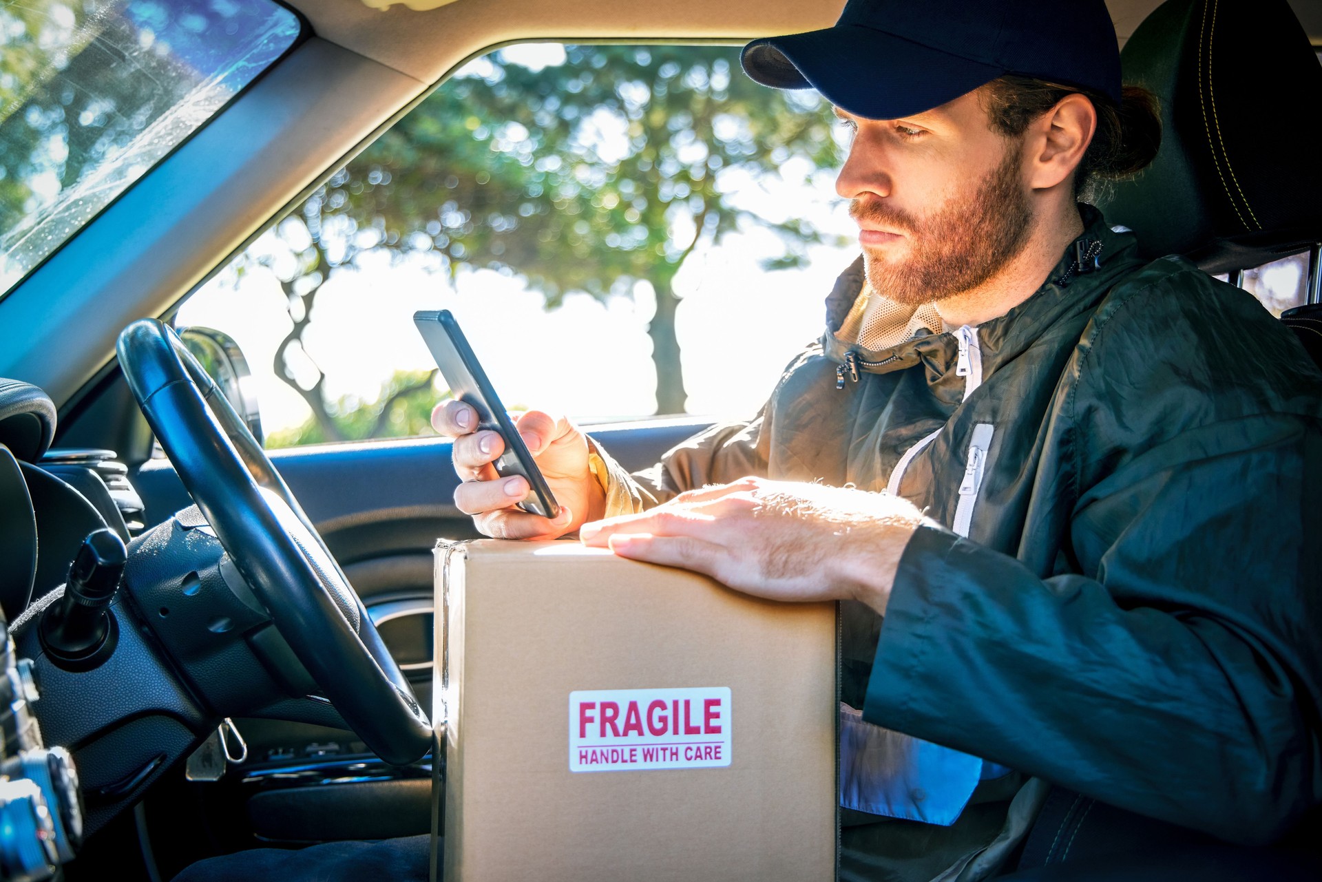 Cropped shot of a handsome young male courier checking his cellphone for directions while making deliveries in his van